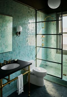 a bathroom with blue tiles and gold fixtures