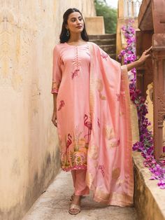 The Rose Pink Handpainted Modal Silk Suit Set with Zari Silk Dupatta is a stunning fusion of elegance and artistry. The suit set is made from luxurious modal silk, known for its soft, smooth texture and graceful drape. The rose pink hue adds a delicate, feminine charm, while the handpainted flamingo Motifs, bring a unique, artisanal touch to the outfit, making each piece one of a kind. The accompanying zari silk dupatta, woven with intricate gold  zari threads, adds a touch of opulence with its shimmering borders. This ensemble is perfect for special occasions, blending the richness of modal silk with the timeless beauty of traditional hand-painted craftsmanship and luxurious zari detailing. Satin Suit, Set Saree, Delicate Feminine, Silk Suit, Satin Color, Silk Dupatta, Suit Designs, Suit Set, The Rose