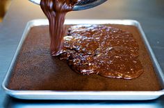 a person pouring sauce into a pan on top of a table