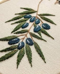 a close up of a embroidery on a piece of cloth with blue and green leaves