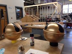 two large metal balls sitting on top of a wooden table next to a bottle of paint