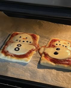 two pizzas that have been made to look like ghost faces on them, sitting in an oven