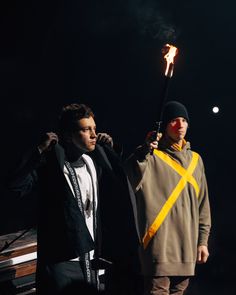 two men standing next to each other holding torches