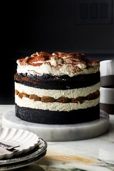 a layered cake sitting on top of a white plate next to a cup and saucer