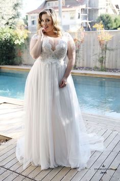 a woman in a white dress standing by a pool