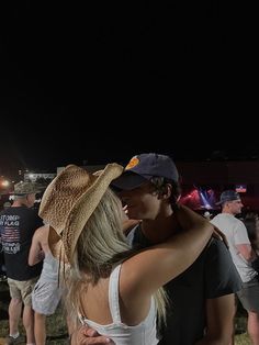 a man and woman standing next to each other in front of a crowd at night