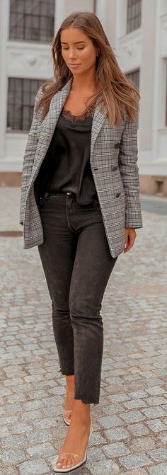 a woman in black and white checkered blazer walking on cobblestone street