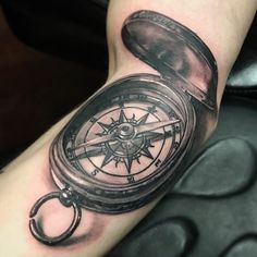 a man's arm with a compass tattoo on it and a pocket watch in the middle