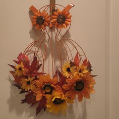 a metal wreath with sunflowers and leaves hanging on a white wall next to a door