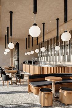 the interior of a restaurant with wooden tables and black leather seats, hanging lights and round pendants