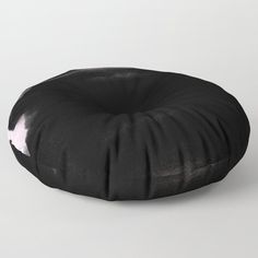 a black round pillow sitting on top of a white floor