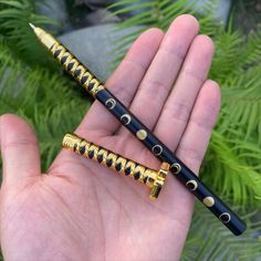 two black and gold colored pens sitting on top of each other in someone's hand