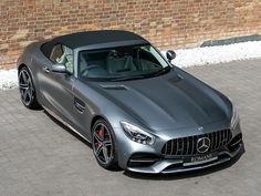 a silver mercedes sports car parked in front of a brick wall