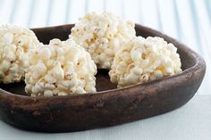 some kind of food that is in a wooden bowl on a white tableclothed surface