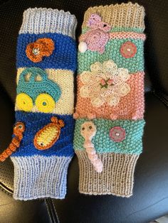 two knitted mittens with animals and flowers on them sitting on a black chair