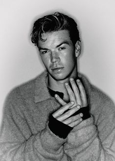 a black and white photo of a young man with his hands on his chest, posing for the camera