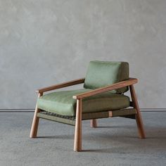 a green chair sitting on top of a cement floor next to a wall with a wooden frame