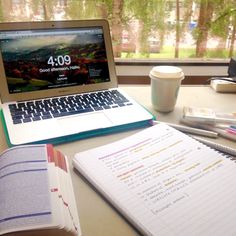 an open laptop computer sitting on top of a desk next to a cup of coffee