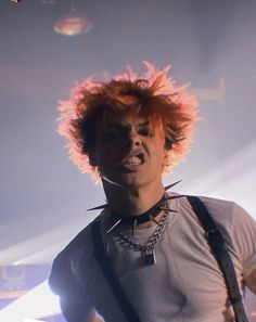 a young man with red hair and piercings on his neck is playing an electric guitar