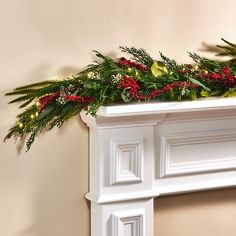 a white mantle decorated with greenery and red berries