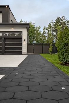 a driveway leading to a modern house with black and white accents on the front door