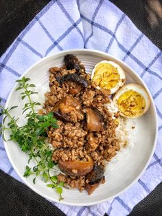 a white plate topped with rice and meat next to an egg on top of it