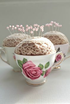 three teacups with pins in them sitting on a table