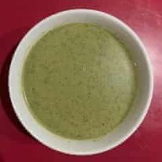 a white bowl filled with soup on top of a red table