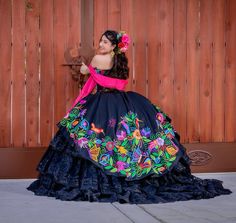 a woman in a colorful dress leaning against a wooden fence with her hand on the door