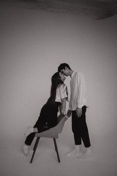 black and white photograph of two people kissing on a chair in front of a wall