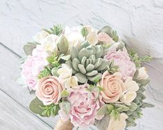 a bridal bouquet with pink roses and succulents on a white wooden background