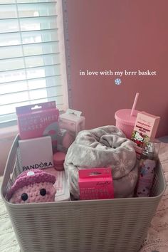 a basket filled with lots of items on top of a bed next to a window