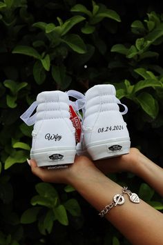 a pair of white tennis shoes on someone's hand