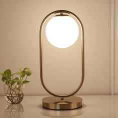 a table lamp sitting on top of a white counter next to a potted plant