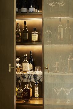 an open cabinet with bottles and glasses on the shelf in front of it, which is also labeled all posts