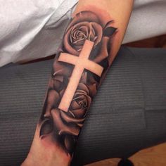 a person with a cross and roses tattoo on their arm