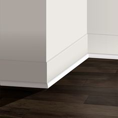 the corner of an empty room with wood flooring