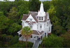 an aerial view of a large white house with a steeple and trees surrounding it