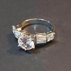 an engagement ring with three baguets on the side and one diamond in the middle