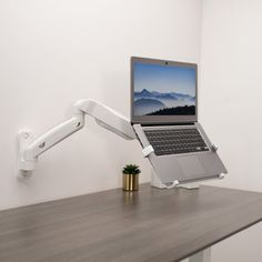 a laptop is sitting on a desk with a monitor arm attached to the back of it