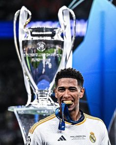 the soccer player is posing with his trophy in front of him and looking at the camera