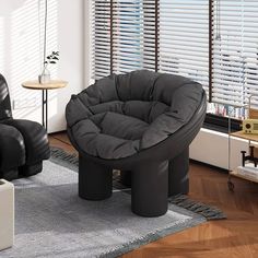 a living room with two black chairs and a round ottoman in the middle of it