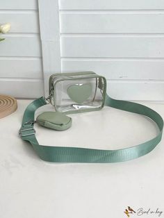 a green camera strap with a heart shaped button on the front and an apple in the back