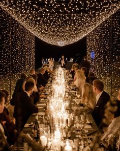 a long table with many people sitting at it and lit up the room in white lights