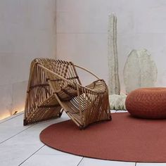 two wicker chairs sitting on top of a rug next to a white wall and floor