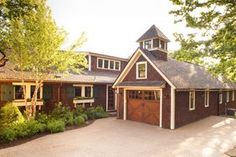 a large house with a garage in the middle of it's driveway surrounded by trees