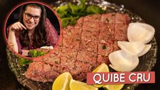 a woman sitting in front of a plate of food with lemons, onions and meat