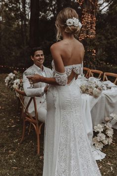 a man and woman standing next to each other in front of a table with flowers