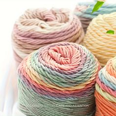 several skeins of multicolored yarn sitting on a white plate with green leaves