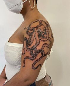 a woman wearing a surgical mask with an octopus tattoo on her left shoulder and chest